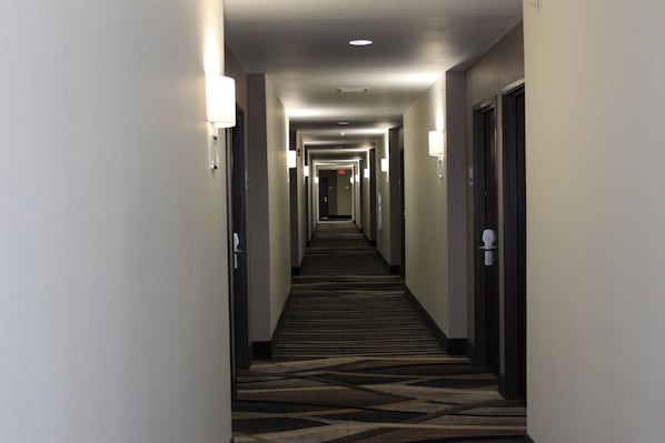 Corredor de hotel com pisos cobertos por carpete e portas em ambos os lados.
