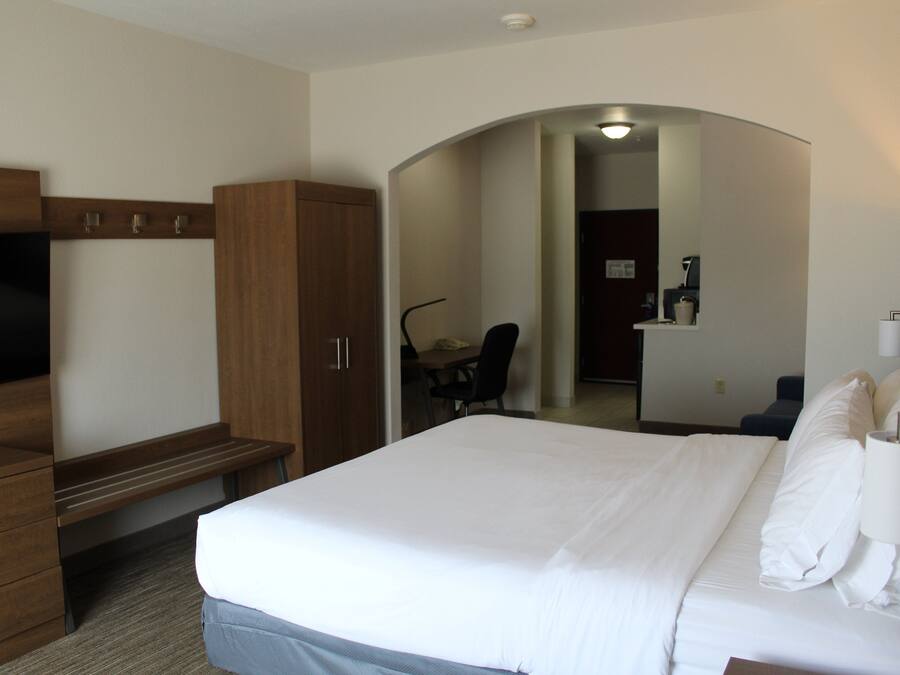 Une chambre d’hôtel avec un lit, un bureau, une chaise, une télévision et une salle de bain visible à travers une arche.