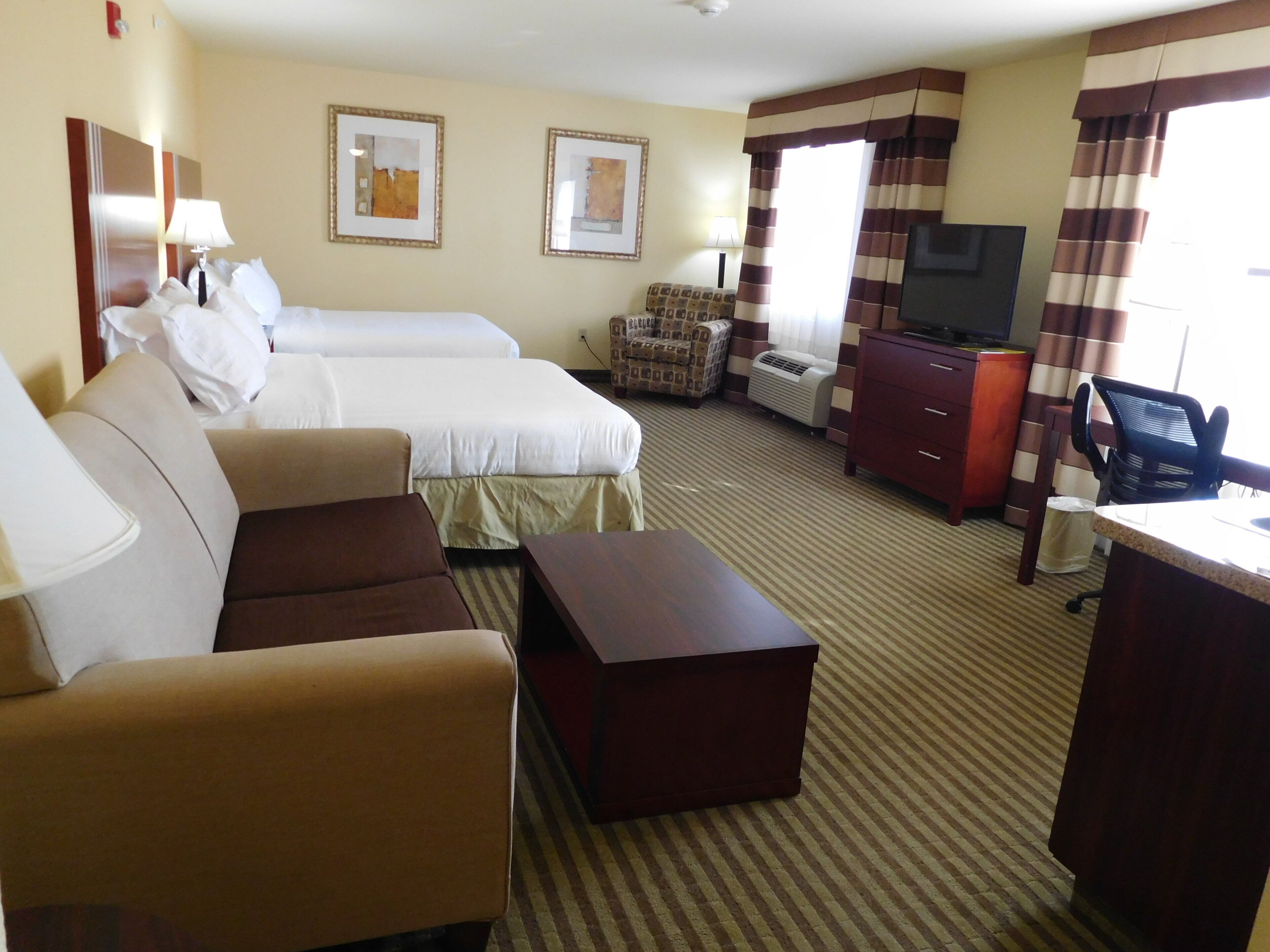 Ein Hotelzimmer mit Bett, Sofa, Schreibtisch, Fernseher und Stuhl.