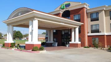 A hotel with a covered entrance, a brick facade, and a sign for Hilton Express.