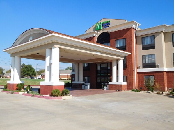 A hotel with a covered entrance, a brick facade, and a sign for Hilton Express.