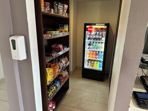 Máquina automática reabastecida com lanches e bebidas, incluindo batatas fritas, doces e refrigerantes.