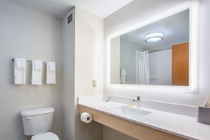 Un baño moderno con inodoro, lavabo y espejo.