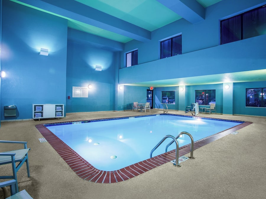 Una piscina con borde de ladrillo rojo, rodeada de paredes azules y un techo con iluminación empotrada.