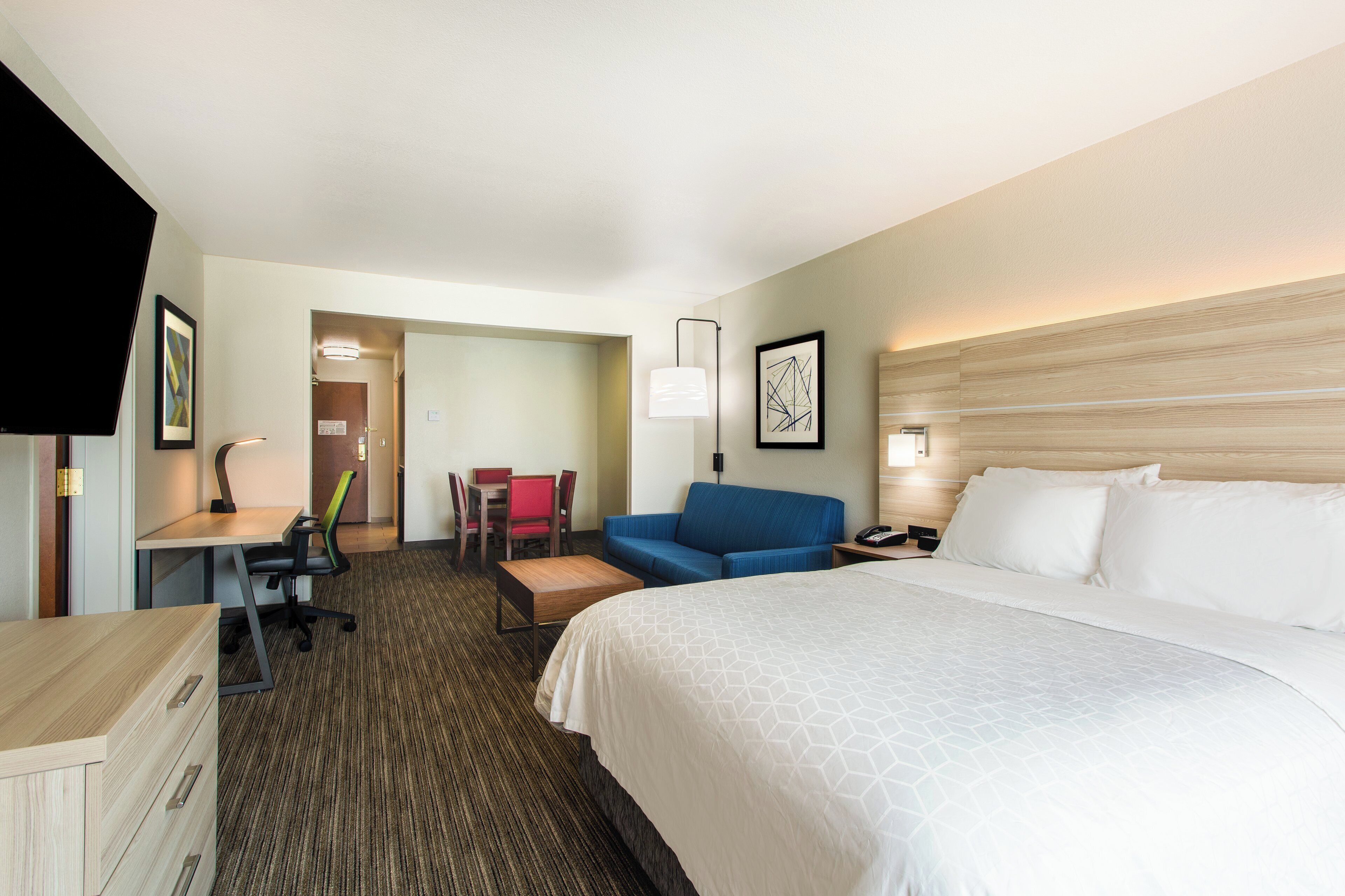 Una habitación de hotel con cama, escritorio, sillón, sofá y mesa de comedor.