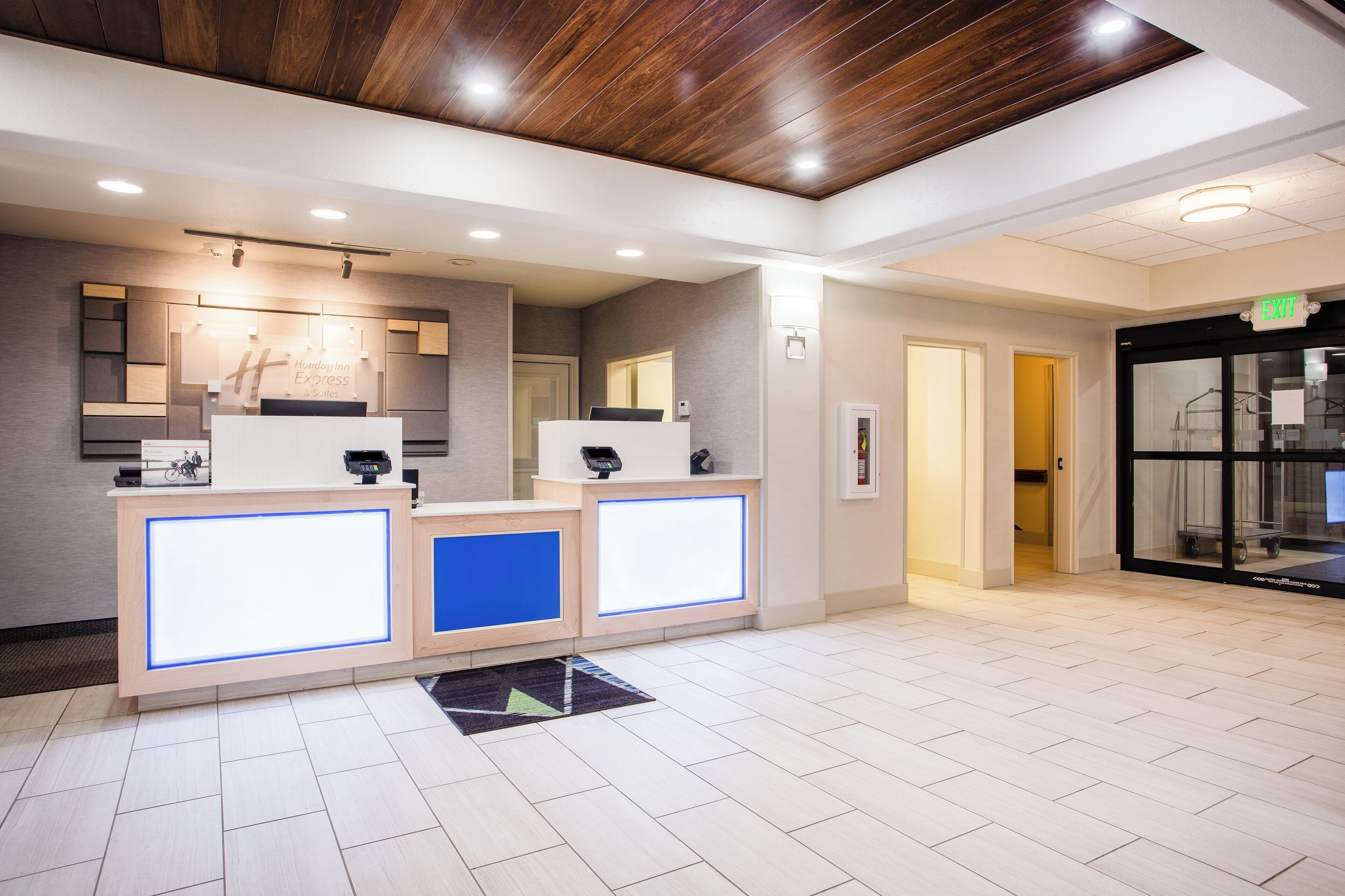 A hotel reception area with a wooden ceiling, a reception desk, and a sign indicating the exit.