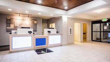 A hotel reception area with a wooden ceiling, a reception desk, and a sign indicating the exit.