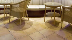 A modern lounge area with a sofa, two wicker chairs, and a small round table. - Buchholz Downtown Hotel (Cologne)