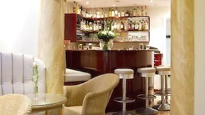 A bar area with a sofa, chairs, and a bar counter with bottles. - Buchholz Downtown Hotel (Cologne)