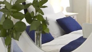 A bedroom with a bed, a bedside table, a lamp, and a painting on the wall. - Buchholz Downtown Hotel (Cologne)