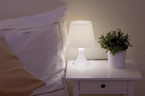 A white bedside table with a lamp and a potted plant. - Buchholz Downtown Hotel (Cologne)