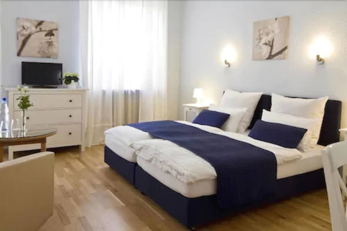 Ein Hotelzimmer mit einem Bett, Nachttischen, einem Schreibtisch und einem Sessel.
