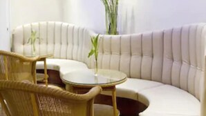A modern living room with a curved sofa, wicker chairs, and a glass coffee table. - Buchholz Downtown Hotel (Cologne)
