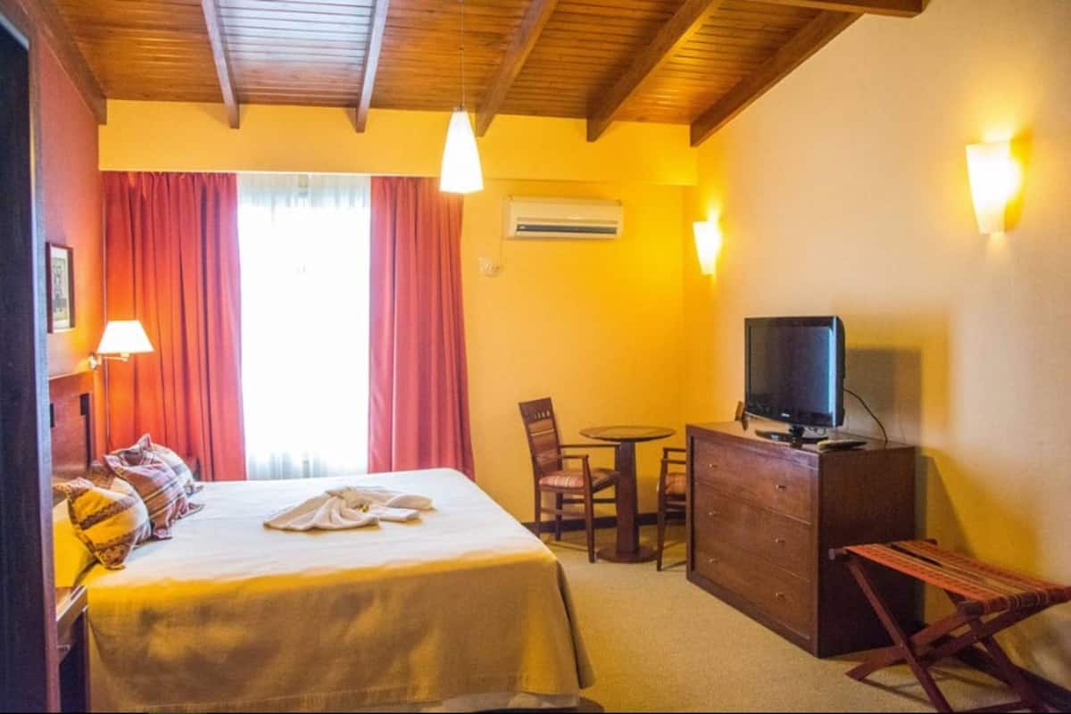 Ein Hotelzimmer mit Bett, Schreibtisch, Fernseher, Sessel und kleinem Tisch.