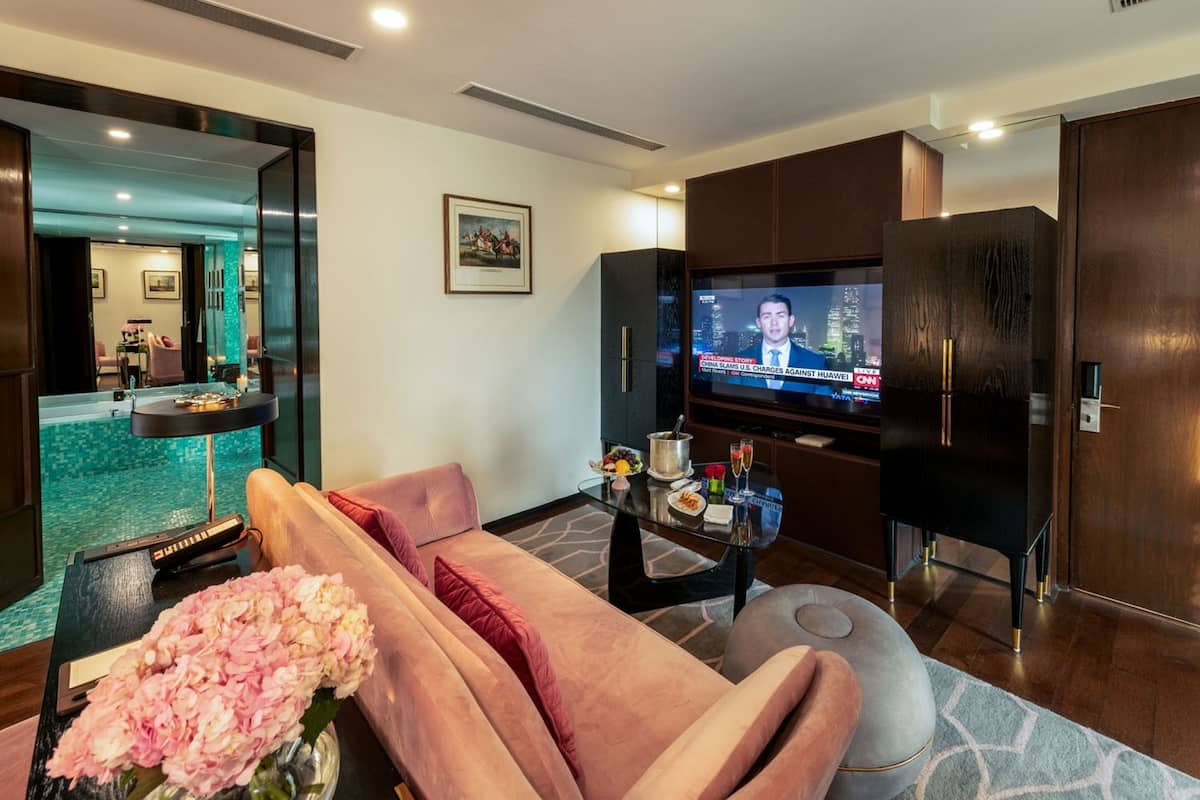 A modern living room with a sofa, a coffee table, a TV, and a pool view.