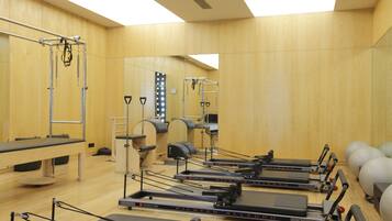 A Pilates studio with equipment and a mirrored wall.
