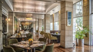 A spacious restaurant with high ceilings, large windows, and a variety of seating arrangements.