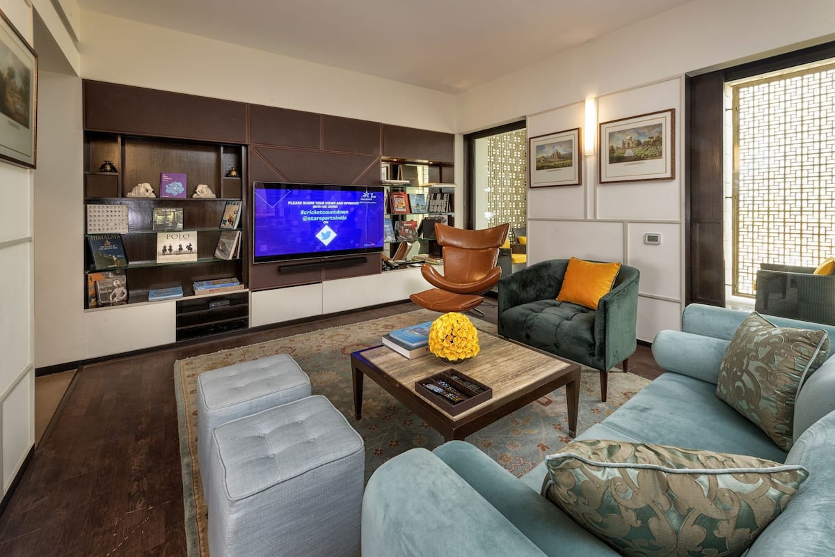 A modern living room with a flat-screen TV, comfortable seating, a bookshelf, and decorative items.