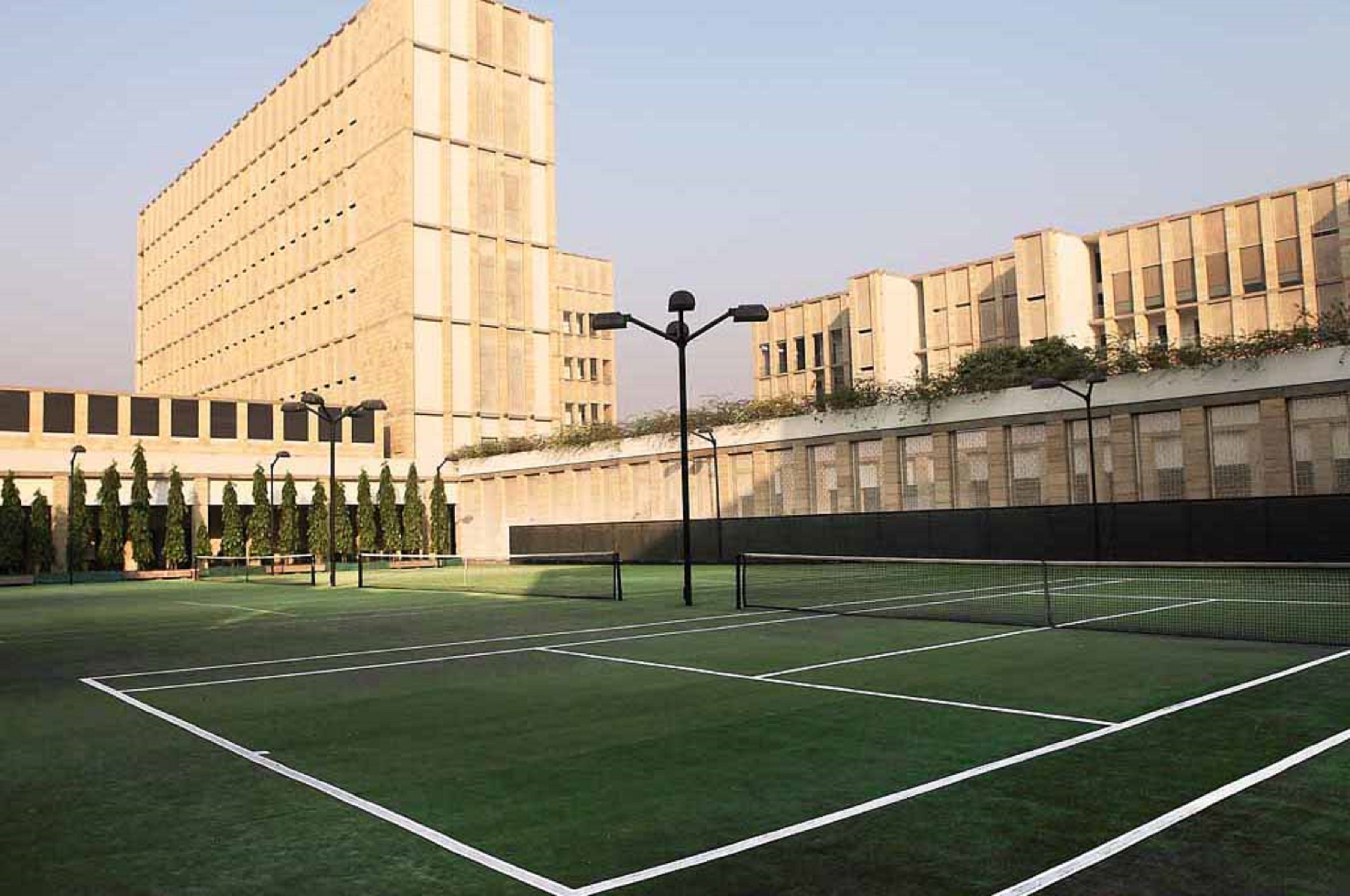 A tennis court with a net, surrounded by buildings with a modern architectural style.