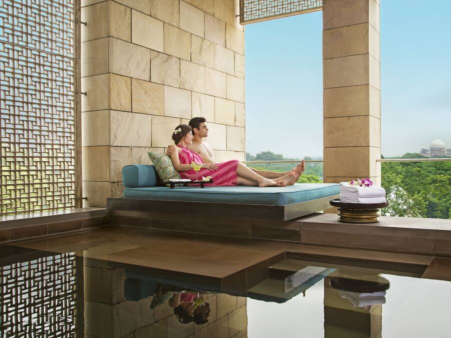 Um casal relaxando em um sofá azul com vista para um prédio grande ao longe.