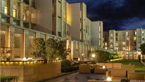 A modern hotel exterior at night with a well-lit pathway, outdoor seating, and a bar area.