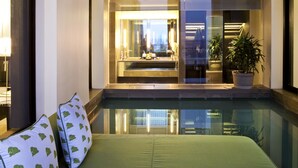 A modern hotel room with a green bed, a large window, and a view of the cityscape.