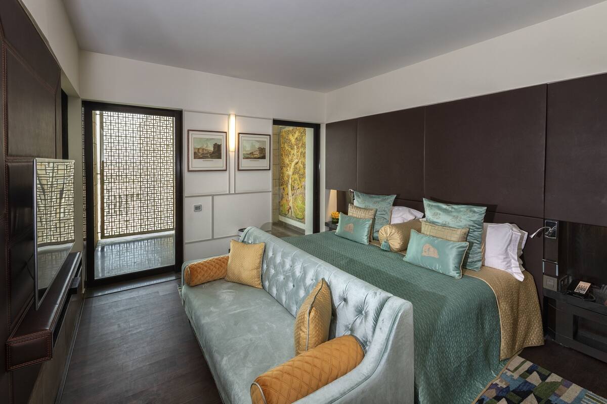 A modern hotel room with a large bed, a sofa, and a desk.