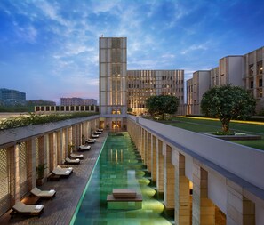 Un hôtel doté d’une piscine centrale, de chaises longues et d’un bâtiment moderne à la façade en verre.