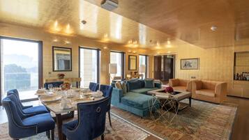 Un vaste espace de vie comprenant une table à manger pour six personnes, un canapé bleu et un fauteuil beige.
