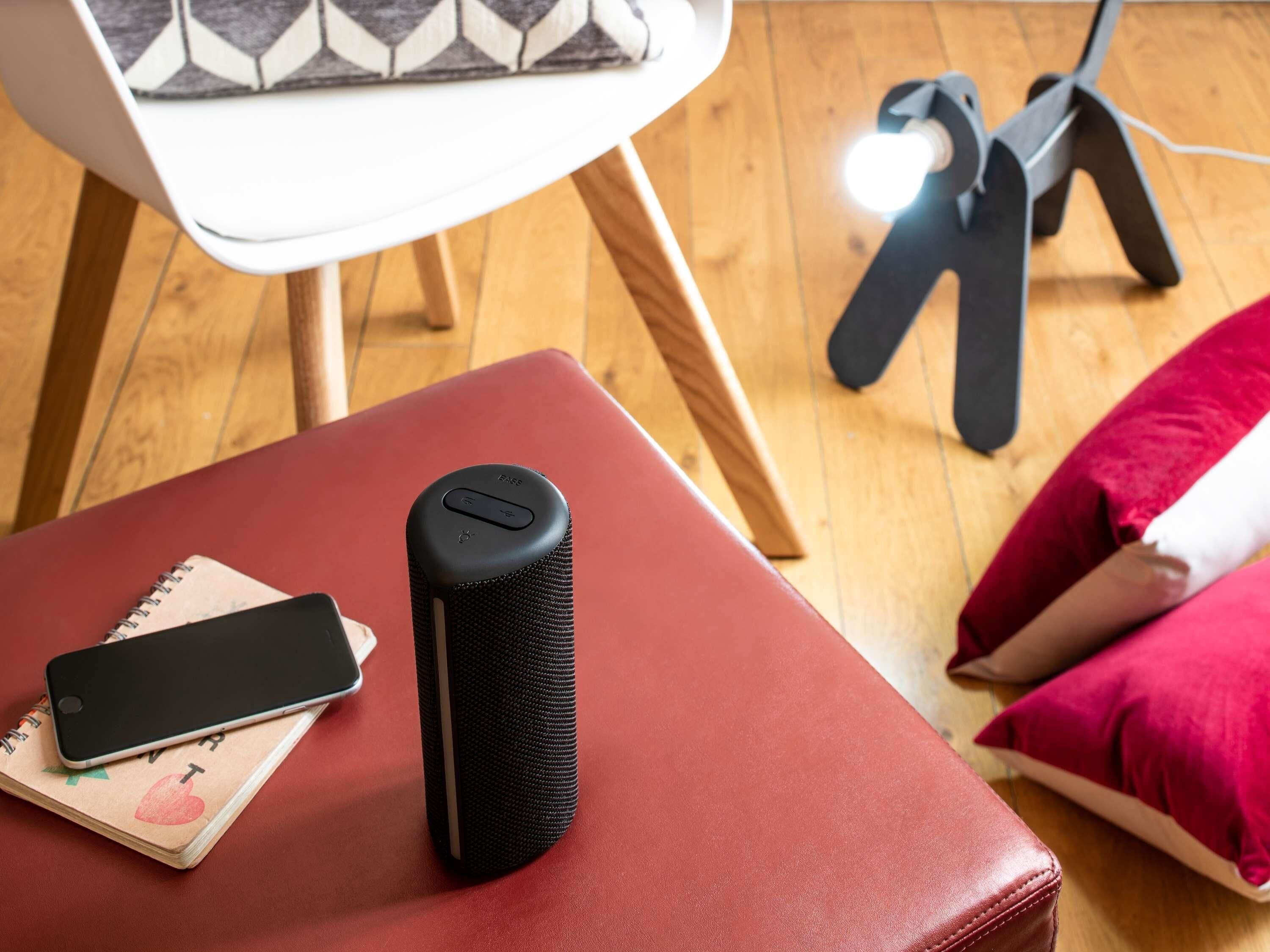 A red ottoman with a smartphone and a black speaker on top.