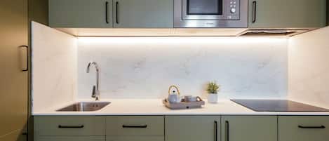 A modern kitchen with a built-in microwave, a stainless steel sink, and a marble countertop.