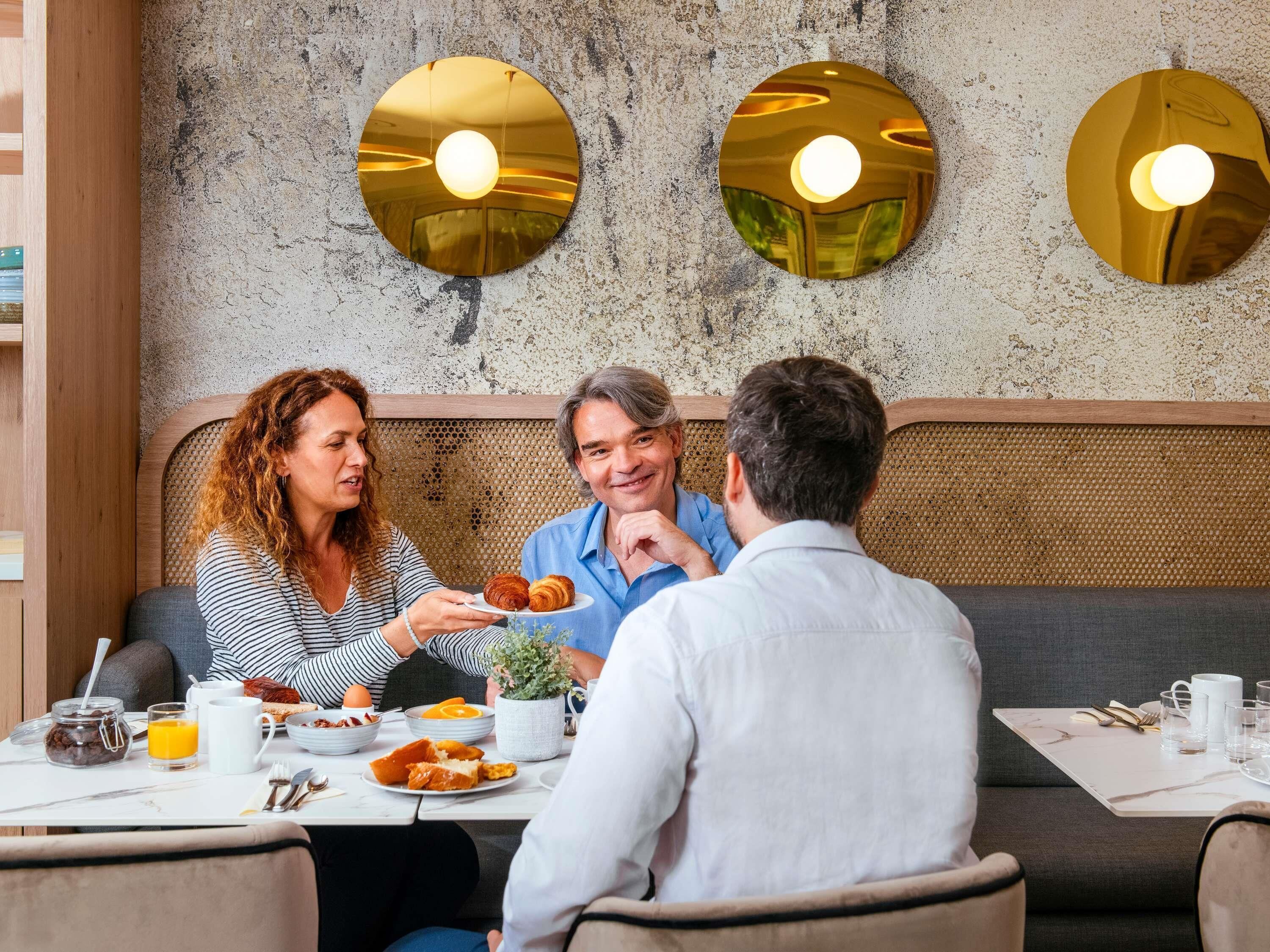 A dining area with a rustic wall, round wall sconces, and a table set for breakfast.