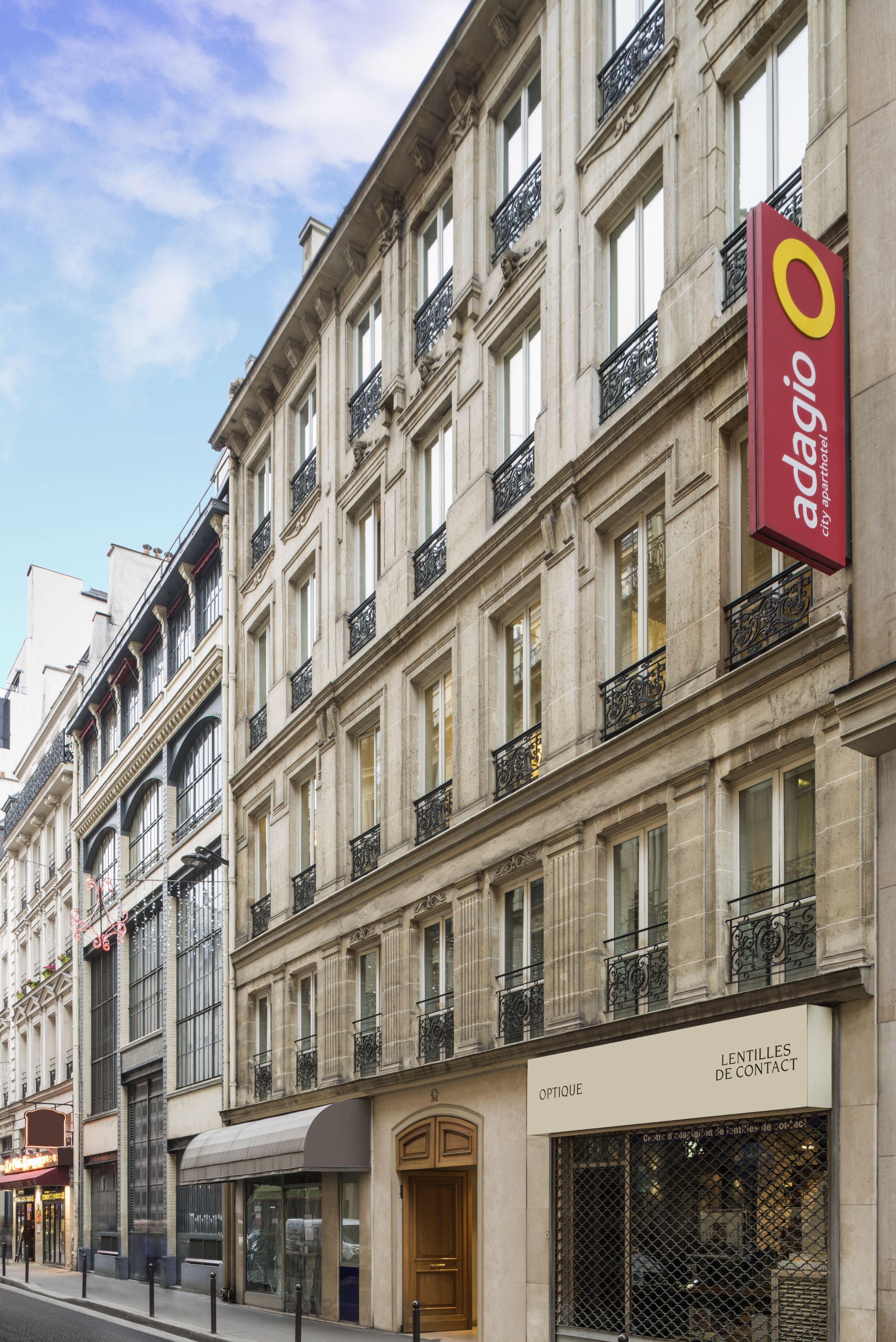 A multi-story building with a prominent red sign for 'adagio' on the right side.
