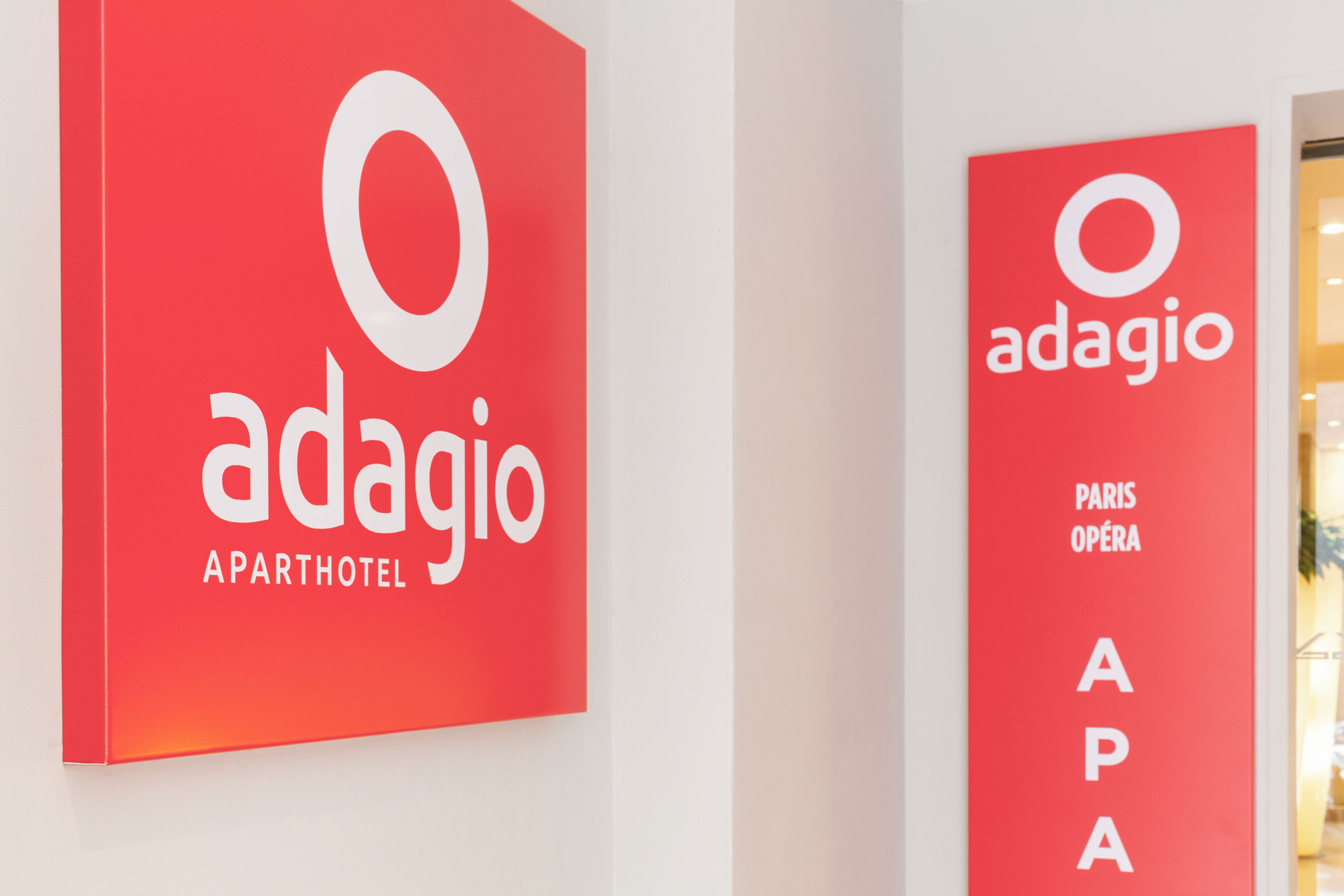 Two red signs with the 'adagio' logo and 'APARTHOTEL' text.