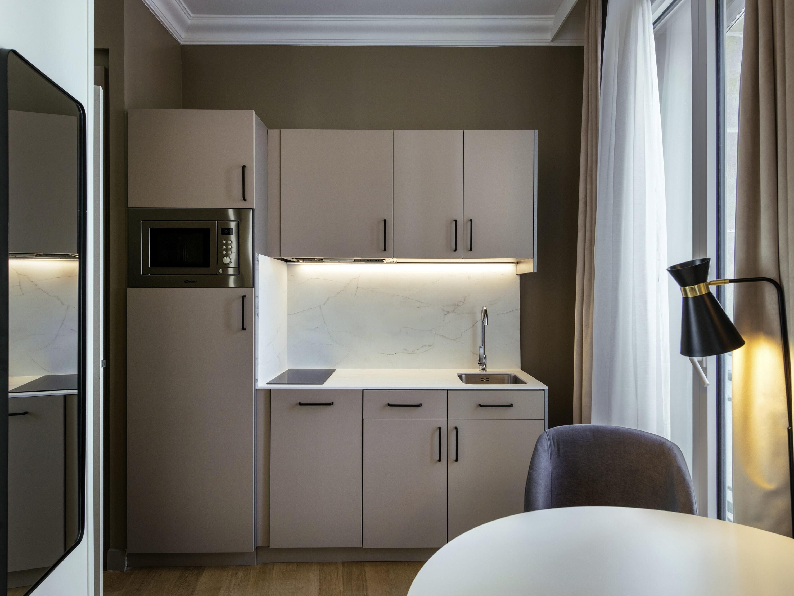 A compact kitchen with a built-in microwave, a sink, and cabinets.