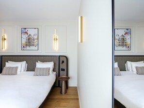 A hotel room with two beds, a small round table, and wall-mounted light fixtures. - Aparthotel Adagio Paris Opéra (Paris)