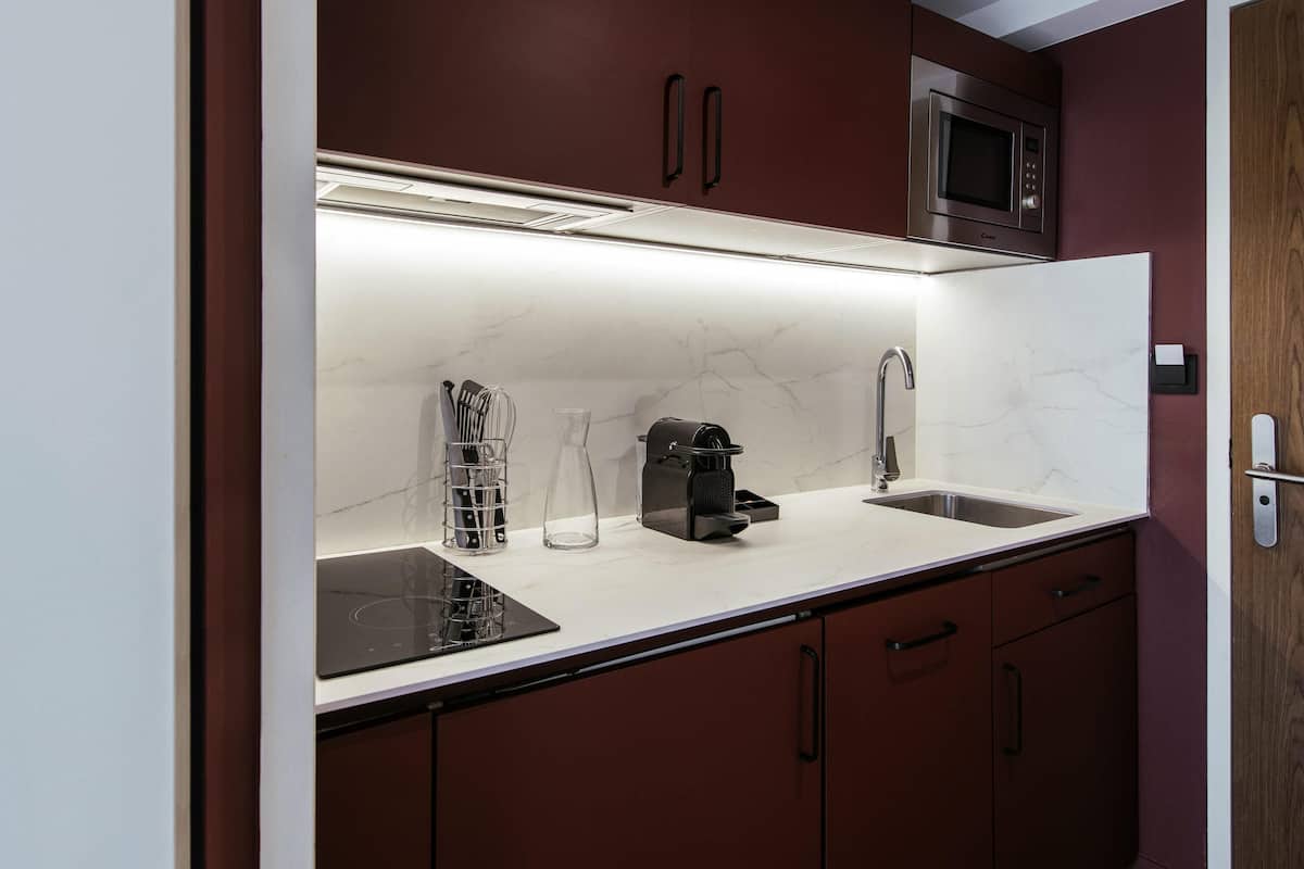 A modern kitchen with a built-in microwave, a coffee machine, and a sink.