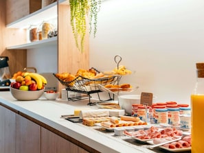 A breakfast buffet with fruits, pastries, and various dairy products.