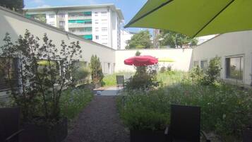 Un patio con un sendero de grava, plantas en macetas y mobiliario exterior.