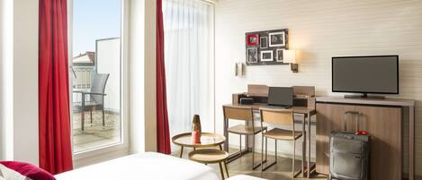 Een hotelkamer met twee bedden, een bureau met een computer, een televisie en een koffer.