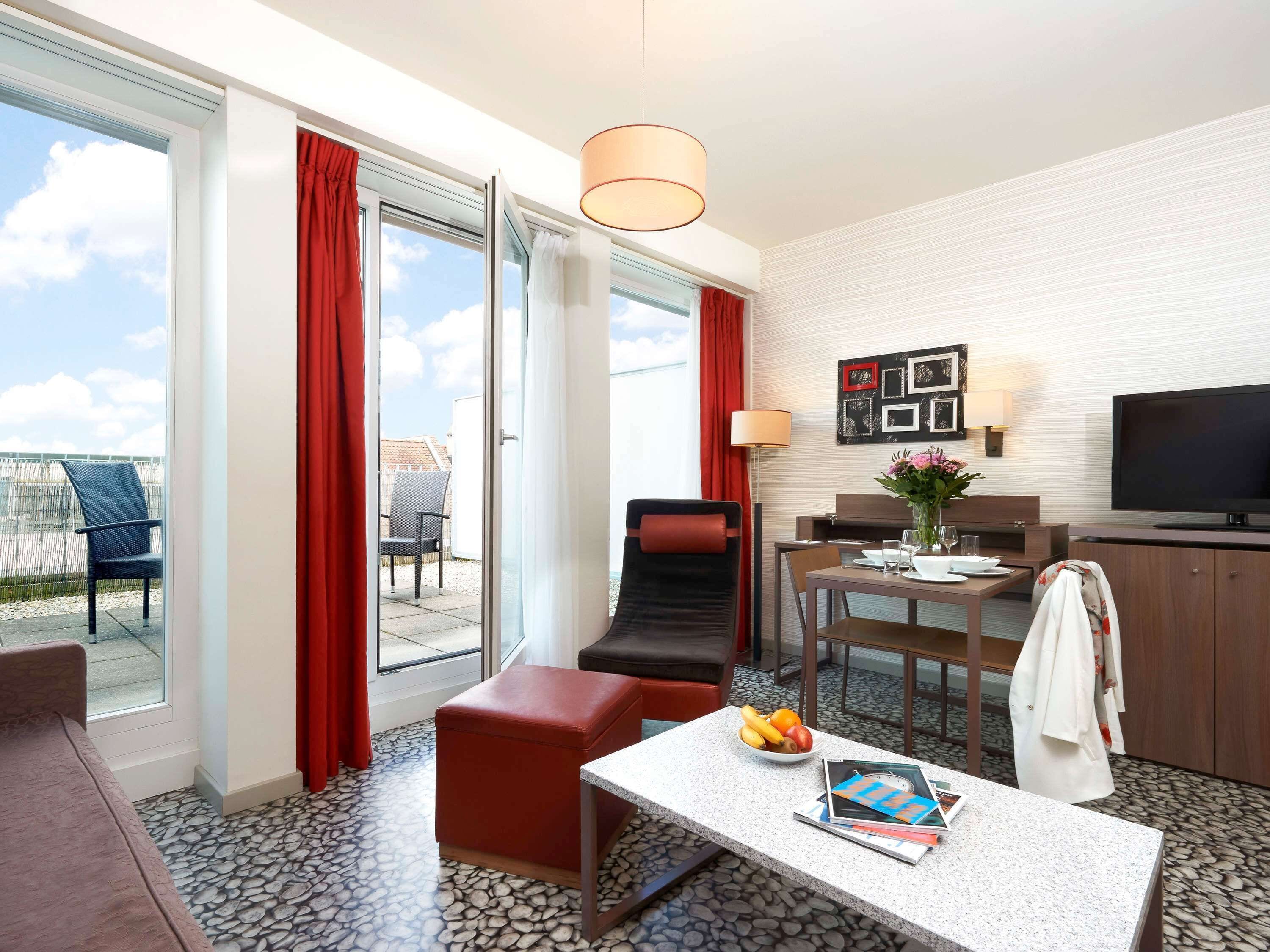 Habitación de hotel con comedor, televisión y vistas al exterior.