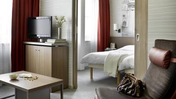 A hotel room with a bed, a TV, a desk, and a chair.