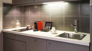 A modern kitchen with grey cabinets, a stainless steel sink, and a coffee machine.