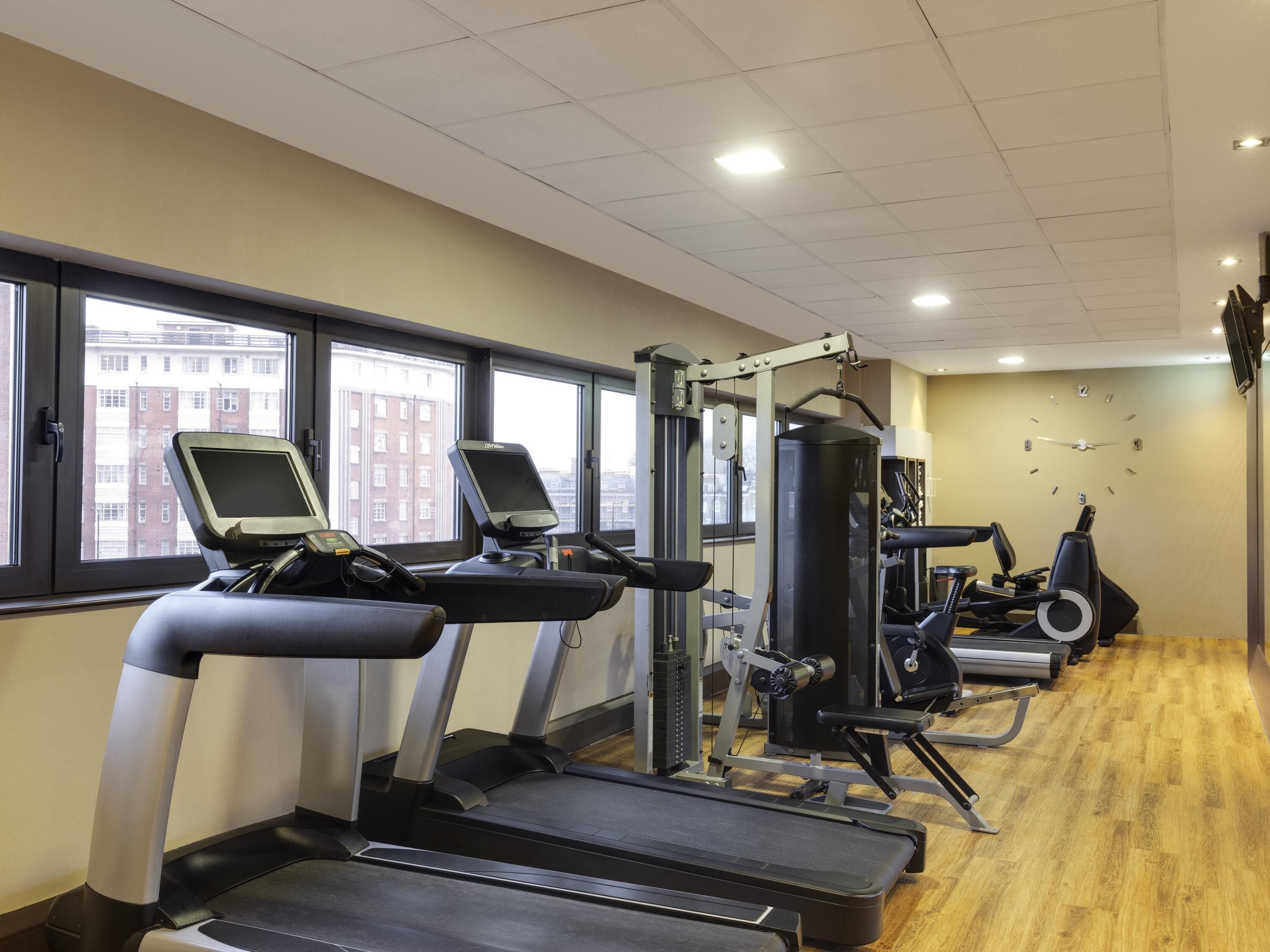 A gym with treadmills, a weight machine, and a wall clock.
