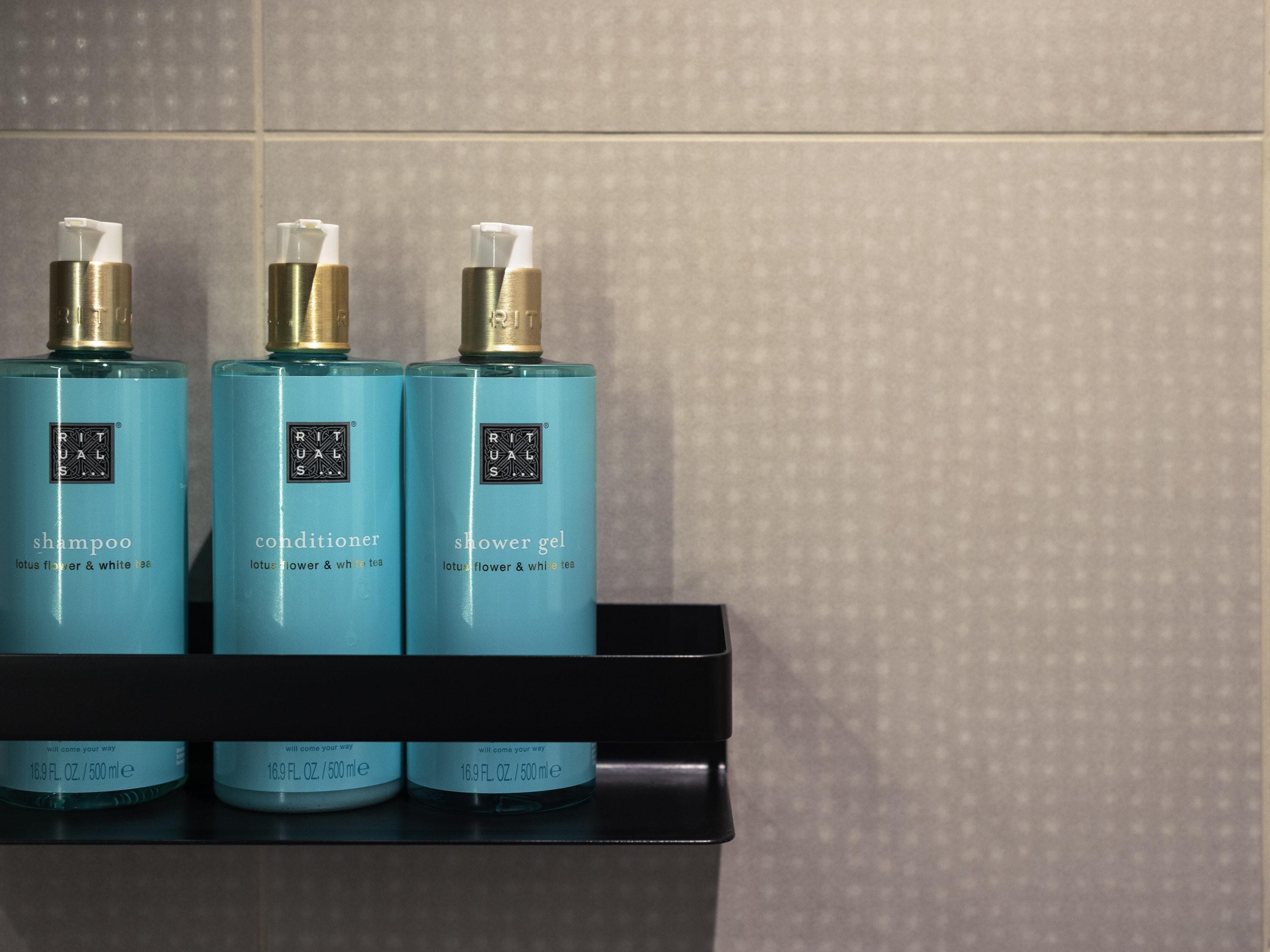 Three bottles of Rituals products on a black shelf.