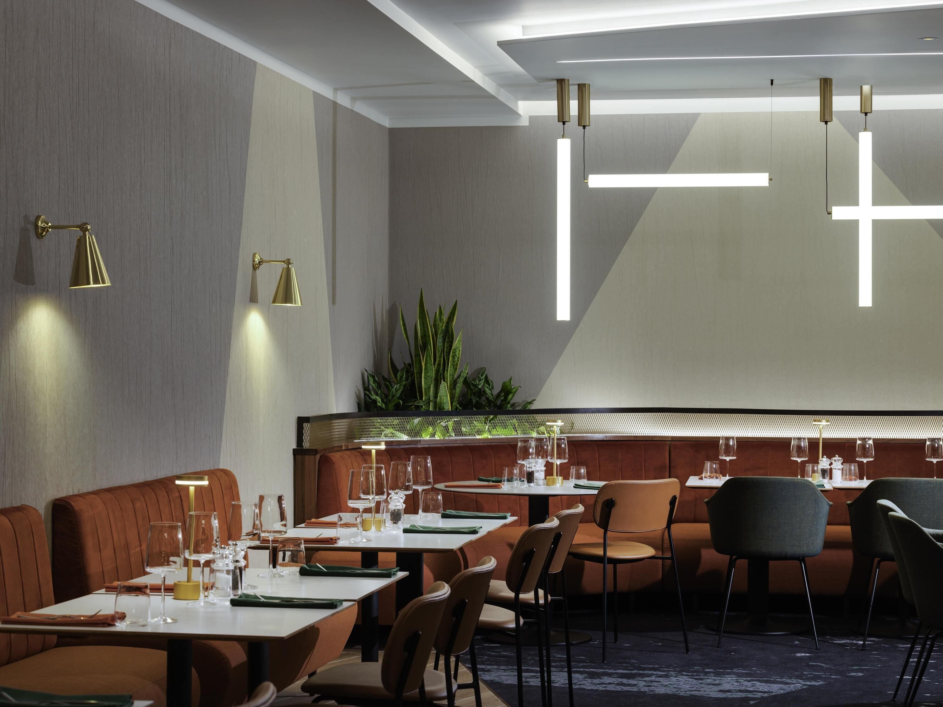 A modern restaurant with high tables, cushioned booths, and pendant lighting.