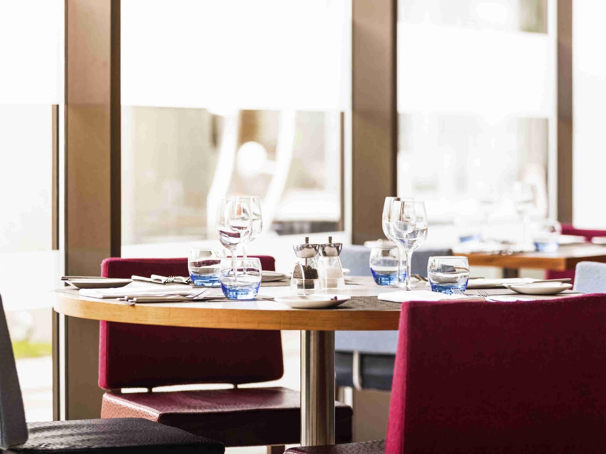 A restaurant setting with tables, chairs, and dining ware.