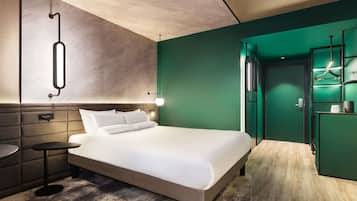 Ein modernes Hotelzimmer mit einem Bett, einem Nachttisch und einer grünen Wand.