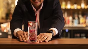A person in a dark suit at a bar with a drink in front of them. - Novotel London Paddington (London)