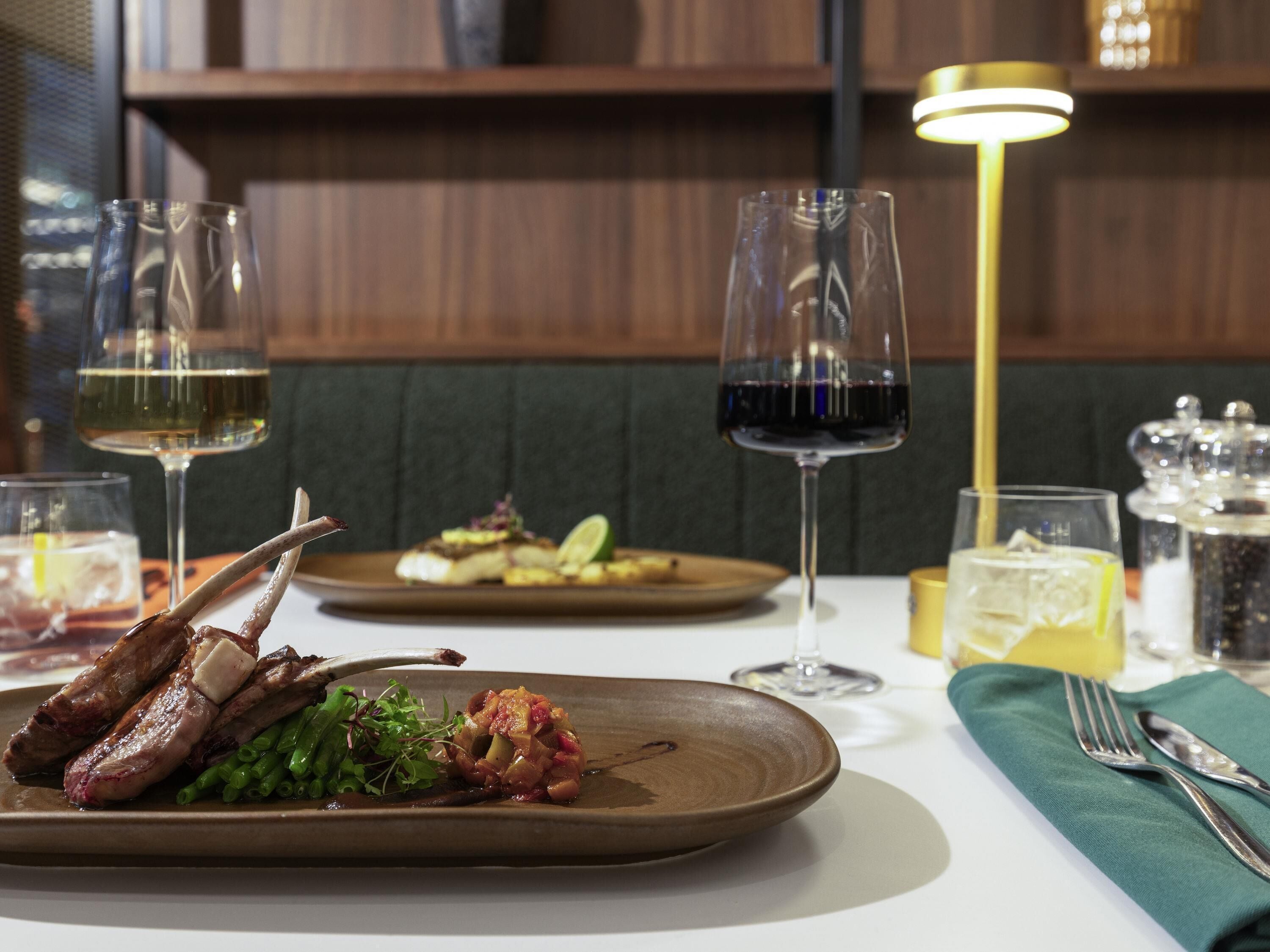 A dining table with plates of food, glasses of wine, and cutlery.